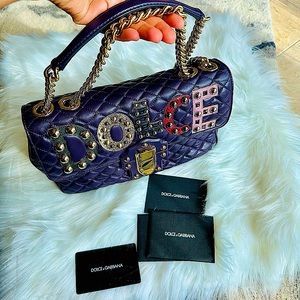 A Dolce & Gabbana hand bag with an embroidered logo in metallic accents..